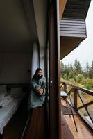 femme assise sur le rebord de la fenêtre et regarde les montagnes photo