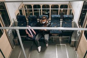 jeune femme avec masque voyageant dans les transports en commun. photo