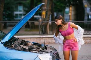 femme avec une voiture cassée sur la route. chercher de l'aide. photo