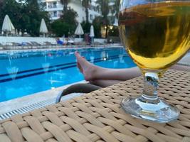 Gobelet en verre de délicieuse bière glacée fraîche fraîche devant la piscine en vacances dans un complexe tropical photo