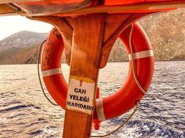 bouée de sauvetage orange sur le navire. croisière. pour sauver les passagers, un cercle d'air en caoutchouc est suspendu. équipement de sauvetage sous un auvent sur fond de mer photo