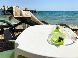 vacances à la mer sur la plage. au sol se trouvent des accessoires de natation, des lunettes de plongée vert clair. nager en haute mer photo