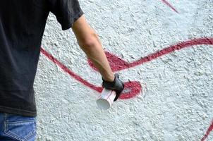 un jeune hooligan peint des graffitis sur un mur de béton. concept de vandalisme illégal. art de rue photo