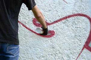 un jeune hooligan peint des graffitis sur un mur de béton. concept de vandalisme illégal. art de rue photo