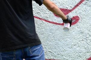 un jeune hooligan peint des graffitis sur un mur de béton. concept de vandalisme illégal. art de rue photo