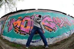 un jeune homme dans un sweat à capuche gris peint des graffitis en rose et vert c photo