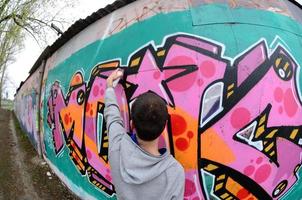 un jeune homme dans un sweat à capuche gris peint des graffitis en rose et vert c photo