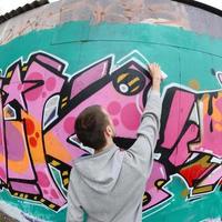 un jeune homme dans un sweat à capuche gris peint des graffitis en rose et vert c photo