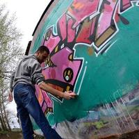 un jeune homme dans un sweat à capuche gris peint des graffitis en rose et vert c photo