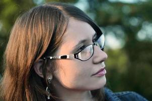 fille à lunettes et veste en jean repose sur le toit d'une maison photo