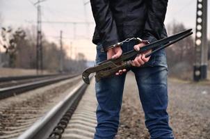 la jeune fille menottée avec la clé à pipe sur le fond de la voie ferrée. le concept de prévention de la criminalité avec la participation du chemin de fer et des trains. photo