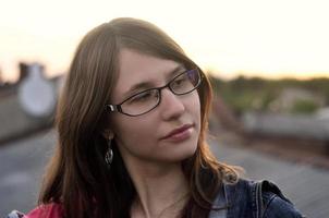 fille à lunettes et veste en jean repose sur le toit d'une maison photo