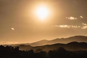 paysage de coucher de soleil avec éclairage doré de montagne et de soleil sous un ciel de soirée coloré et vibrant dans les montagnes. nature montagne ciel et nuages coucher de soleil concept photo