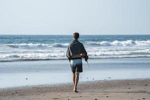 vue arrière de l'homme avec une serviette marchant sur la plage pendant l'été photo