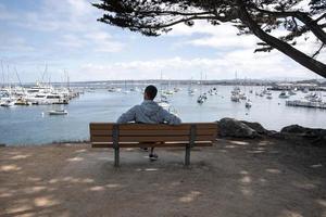 homme regardant des bateaux et des navires naviguant sur le paysage marin assis sur un banc photo