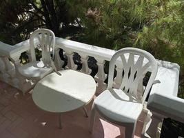 tasse avec des plantes en pots avec un ordinateur portable sur une table en métal blanc sur un balcon en plein air photo