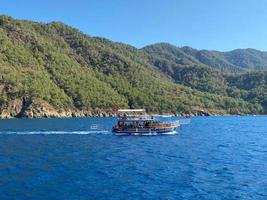 beau bateau de tourisme, yacht de croisière sur le fond de la mer bleue avec de l'eau et des montagnes dans un pays tropical du sud photo