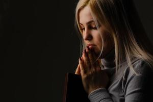 une femme tient et serre la bible sur sa poitrine le matin. la bible est une couverture noire. photo