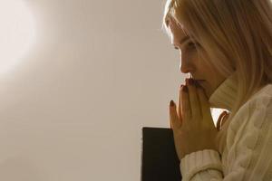 une jeune femme en prière sous une lumière dramatique. photo