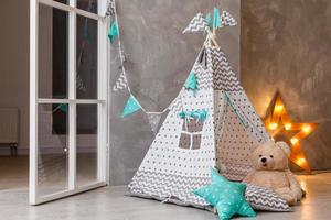 chambre d'enfant moderne et élégante. wigwam pour enfants dans la chambre des enfants. grande lampe étoile en bois. style scandinave intérieur. photo