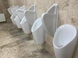 une rangée d'urinoirs dans un mur carrelé dans des toilettes publiques photo
