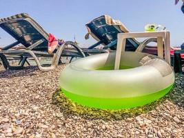 vacances à la mer sur la plage. au sol se trouvent des accessoires de natation, une bouée de sauvetage en caoutchouc pour un enfant vert clair photo