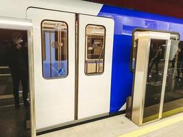 tunnel du métro. les voitures de métro sont protégées par des portes en plastique pour la sécurité des passagers. des wagons de métro bleus transportent les gens dans les stations. porte spacieuse pour handicapés photo