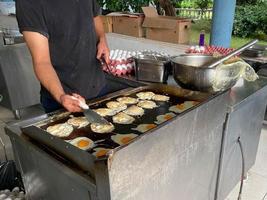 chef, cuisinier cuisine beaucoup d'œufs sur la cuisinière, œufs brouillés dans un restaurant dans une cuisine ouverte dans un hôtel tout compris dans un complexe touristique paradisiaque de pays tropical chaud en vacances photo