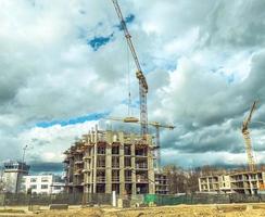 construction d'un nouveau microquartier en centre-ville. une maison en blocs de béton est érigée par une grue jaune. construction d'un immeuble résidentiel à plusieurs étages photo