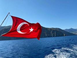gros plan du drapeau de la turquie agitant au-dessus de la mer contre un ciel clair photo