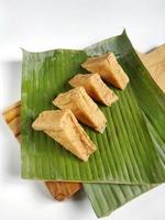 tofu frit en ligne sur des feuilles de bananier et une planche à découper en bois. isolé sur fond blanc photo