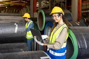 ingénieur asiatique inspectant l'intérieur de l'usine de fabrication de tôles d'acier tout en regardant l'ordinateur portable pour surveiller l'amélioration de la capacité et de la productivité photo