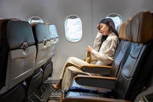 une femme asiatique se sent étourdie et tient à vomir un sac pendant le vol dans l'avion en raison du mal des transports et du mal des transports qui provoque des étourdissements pour l'aérophobie et le transport photo