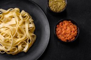 délicieuses pâtes fraîches avec sauce pesto et fruits de mer sur une plaque noire photo