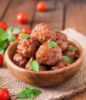 boulettes de viande à la sauce tomate aigre-douce et basilic dans un bol en bois photo