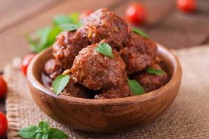 boulettes de viande à la sauce tomate aigre-douce et basilic dans un bol en bois photo