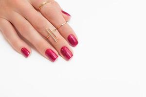vernis gel manucure de couleur magenta viva avec des étincelles sur la main féminine avec des anneaux photo