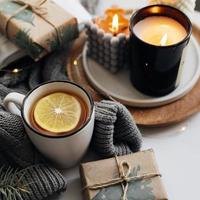 concept confortable de maison d'hiver. thé chaud au citron, livre ouvert, pull chaud, bougies et sapin. bien-être, concept relaxant