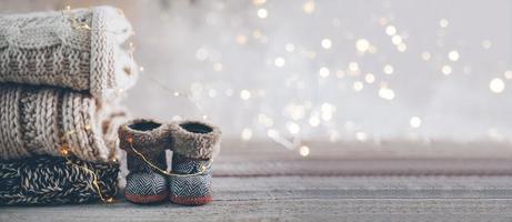 pile de chandails tricotés d'hiver confortables et de jolies petites bottes sur un arrière-plan flou avec bokeh. concept cosy chaleureux. bannière imafe pour la conception photo