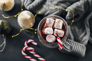 verre avec chocolat chaud avec guimauve sur fond bleu foncé. vue de dessus. photo