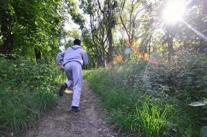 un jeune homme en costume de sport gris court le long du chemin parmi les photo