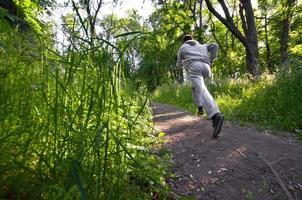 un jeune homme en costume de sport gris court le long du chemin parmi les photo