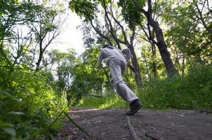 un jeune homme en costume de sport gris court le long du chemin parmi les photo