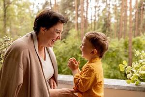 heureuse grand-mère et petit-fils passent du temps ensemble. femme d'âge moyen positive jouant avec un petit petit-enfant mignon, riant, s'amusant. Grand-mère de 50 ans avec petit-enfant. famille multigénérationnelle. photo