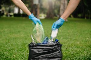 main de personnes tenant une bouteille d'ordures en plastique et en verre mis dans un sac de recyclage. concept de compensation, de pollution, d'écologie et de plastique. photo