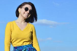 jolie et mignonne fille brune dans un chandail jaune contre un photo