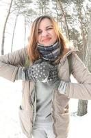 une jeune et joyeuse fille caucasienne en manteau marron sculpte une boule de neige dans une forêt enneigée en hiver. jeux avec de la neige en plein air. photo fisheye