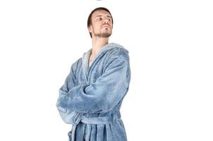 portrait de jeune homme fier barbu caucasien en peignoir bleu avec les mains croisées isolé sur fond blanc photo