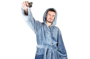 portrait de jeune homme barbu caucasien en peignoir bleu avec arme à feu noire isolé sur fond blanc photo