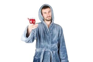 portrait de jeune homme barbu caucasien en peignoir bleu lève un verre de vin rouge isolé sur fond blanc photo